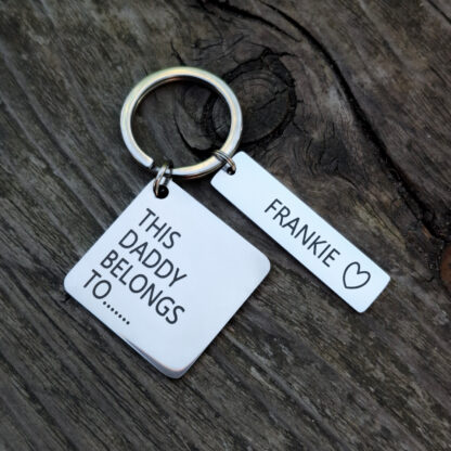 Stainless steel keyring, personalised with your childs name, on a natural wood background